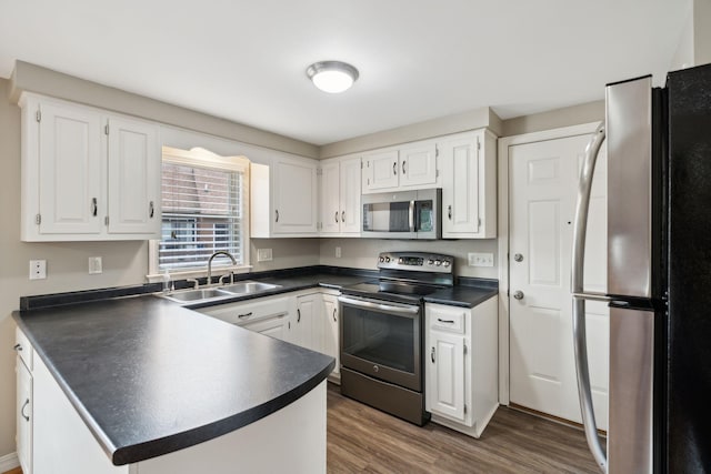 11 Concord Pl Unit 21, Auburn, ME 04210 - kitchen featuring stainless steel appliances, dark countertops, a peninsula, white cabinetry, and dark wood-type flooring