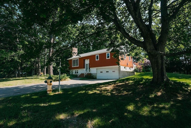 41 Curtis Ln, Milford, ME 04461 - view of front of home featuring an attached garage, a chimney, concrete driveway, and a front lawn