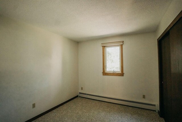 41 Curtis Ln, Milford, ME 04461 - unfurnished bedroom with baseboard heating, carpet floors, and a textured ceiling