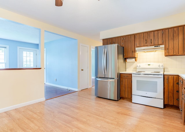 919 College St, Lewiston, ME 04240 - kitchen with white electric stove, freestanding refrigerator, under cabinet range hood, and brown cabinets