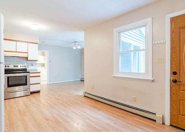 919 College St, Lewiston, ME 04240 - kitchen with stainless steel electric stove, a baseboard radiator, under cabinet range hood, light wood-style floors, and white cabinetry