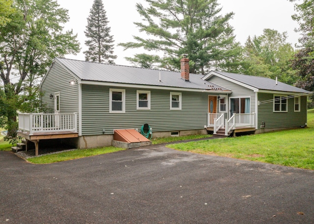 919 College St, Lewiston, ME 04240 - back of property with a chimney, a metal roof, a deck, and a lawn