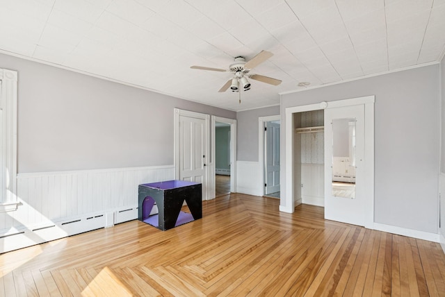 201 Main St, Norway, ME 04268 - unfurnished bedroom featuring a baseboard heating unit, wainscoting, and ceiling fan