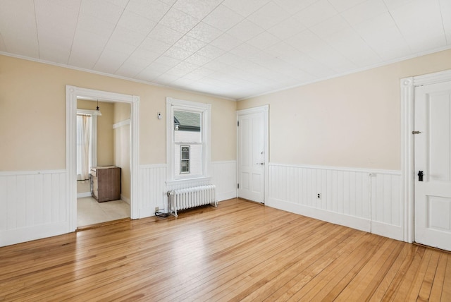 201 Main St, Norway, ME 04268 - unfurnished room with radiator, light wood-style floors, a wainscoted wall, and crown molding