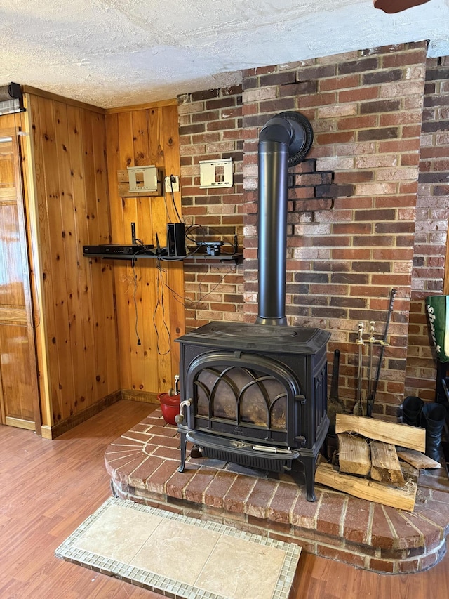 333 Mohawk Rd, Enfield, ME 04493 - detailed view of a wood stove, wood finished floors, a textured ceiling, and wooden walls