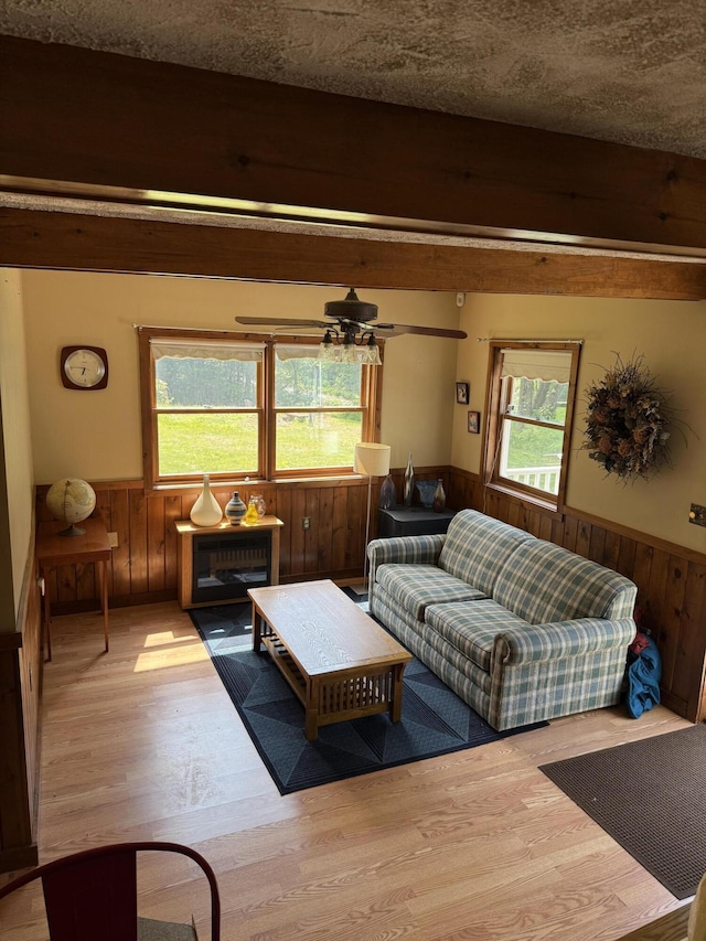 333 Mohawk Rd, Enfield, ME 04493 - living area with wainscoting, wood walls, wood finished floors, beamed ceiling, and a ceiling fan