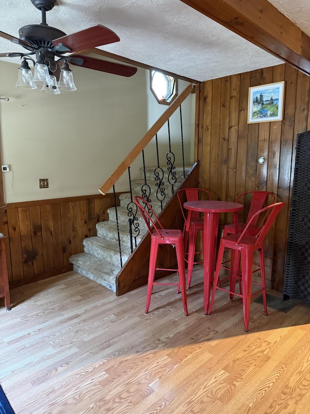 333 Mohawk Rd, Enfield, ME 04493 - dining area featuring wood walls, wood finished floors, a ceiling fan, stairs, and a textured ceiling