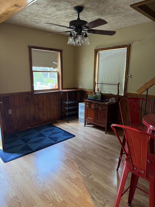 333 Mohawk Rd, Enfield, ME 04493 - living area with wainscoting, ceiling fan, wood finished floors, a textured ceiling, and wooden walls