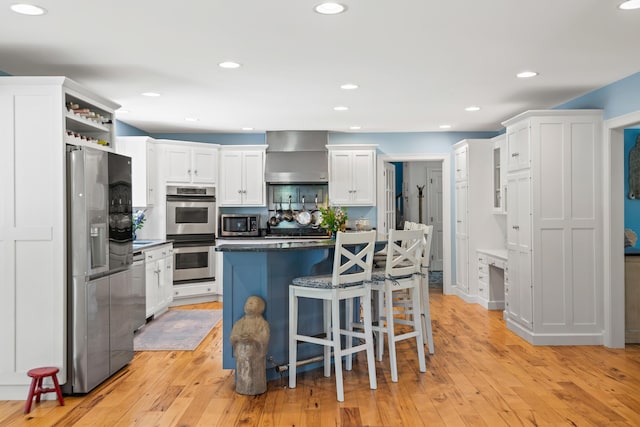 6 Ocean View Dr, Biddeford, ME 04005 - kitchen with appliances with stainless steel finishes, wall chimney exhaust hood, dark countertops, white cabinetry, and a kitchen bar