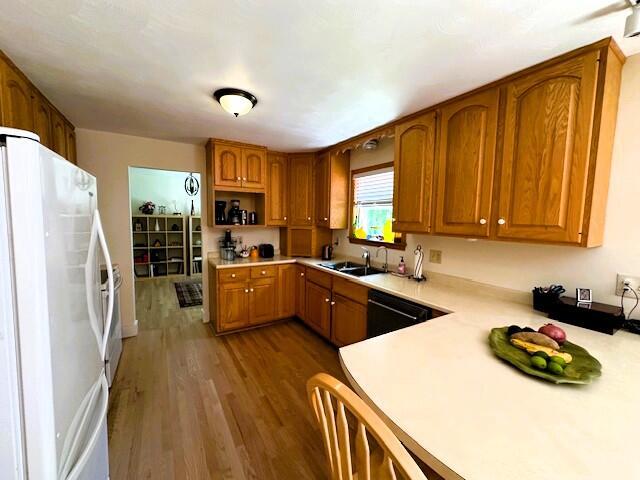 429 Moosehead Trail Highway, Waldo, ME 04915 - kitchen with freestanding refrigerator, light countertops, dishwasher, brown cabinetry, and wood finished floors