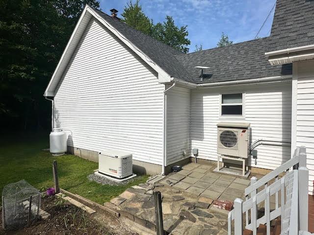 429 Moosehead Trail Highway, Waldo, ME 04915 - view of property exterior with a patio area, a shingled roof, and a lawn