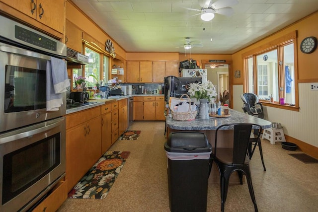 210 Middle St, Farmington, ME 04938 - kitchen featuring stainless steel appliances, ceiling fan, brown cabinetry, light countertops, and a kitchen island