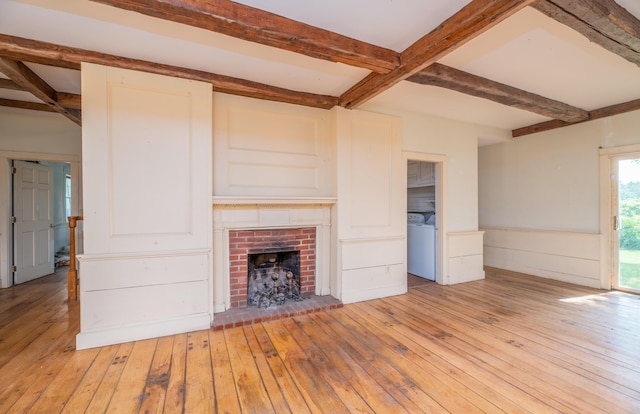 1785 Alna Rd, Alna, ME 04535 - unfurnished living room with beam ceiling, light wood-style floors, a fireplace, a wainscoted wall, and washer and dryer