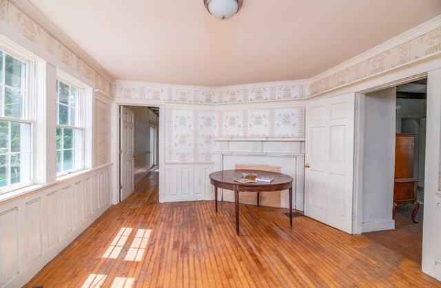 1785 Alna Rd, Alna, ME 04535 - empty room featuring wallpapered walls, light wood-style floors, wainscoting, crown molding, and a decorative wall