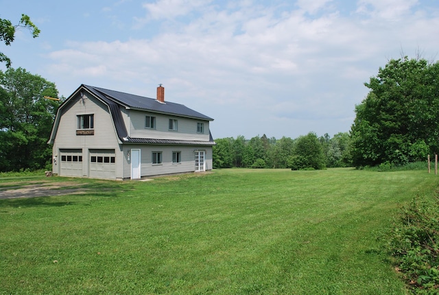 180 Chadbourne Rd, Harmony, ME 04942 - rear view of house featuring a garage, a chimney, a gambrel roof, a metal roof, and a lawn