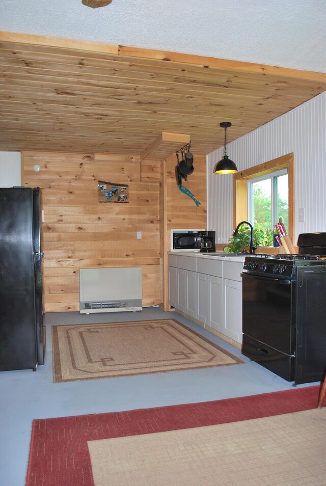180 Chadbourne Rd, Harmony, ME 04942 - kitchen featuring black appliances, wooden walls, decorative light fixtures, wooden ceiling, and white cabinetry