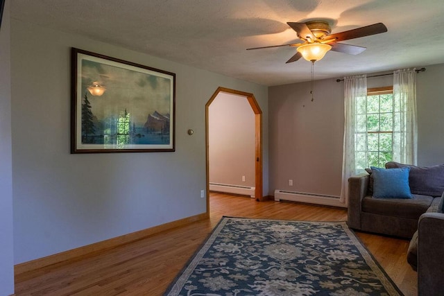 3350 Middle Rd, Sidney, ME 04330 - living room featuring a baseboard radiator, arched walkways, ceiling fan, and wood finished floors