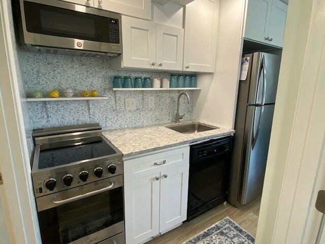 1072 Post Rd Unit 102, Wells, ME 04090 - kitchen with stainless steel appliances, open shelves, light stone countertops, and white cabinetry