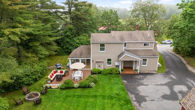 526 E Main St, Yarmouth, ME 04096 - view of front of home with a fire pit, a deck, driveway, a front lawn, and a chimney