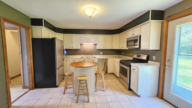 50 George Wright Rd, Woolwich, ME 04579 - kitchen featuring stainless steel appliances, a kitchen island, a kitchen bar, light tile patterned floors, and white cabinetry