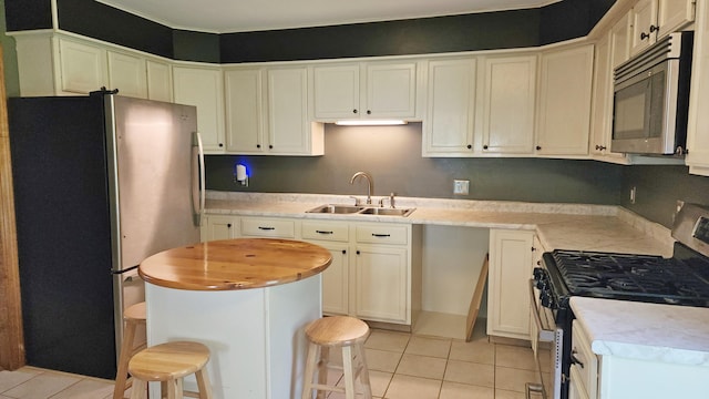50 George Wright Rd, Woolwich, ME 04579 - kitchen with stainless steel appliances, light tile patterned flooring, butcher block counters, and a kitchen bar