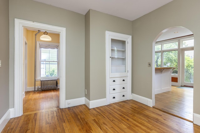 80 Melbourne St, Portland, ME 04101 - unfurnished room featuring radiator heating unit, light wood-style floors, and arched walkways