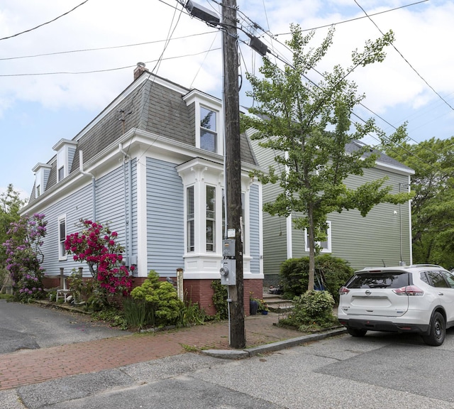 80 Melbourne St, Portland, ME 04101 - view of front facade with roof with shingles, mansard roof, and a chimney