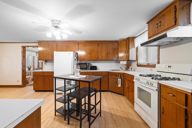 33 Maple St, Limerick, ME 04048 - kitchen featuring white appliances, under cabinet range hood, light wood-type flooring, and brown cabinetry