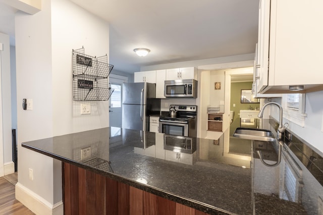 272 Center St, Bangor, ME 04401 - kitchen featuring stainless steel appliances, a peninsula, white cabinets, and dark stone countertops
