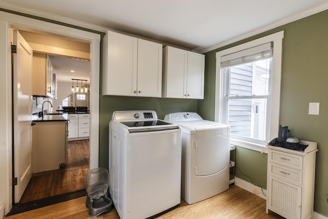 272 Center St, Bangor, ME 04401 - laundry room with washing machine and dryer, light wood-style flooring, cabinet space, and crown molding