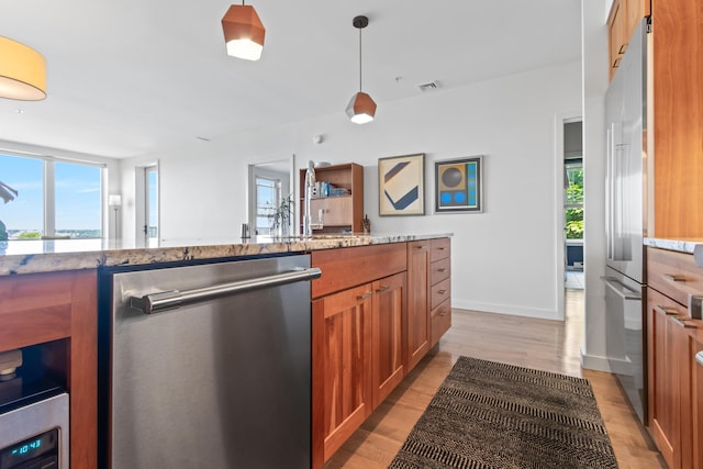 156 Sheridan St Unit 2A, Portland, ME 04101 - kitchen with appliances with stainless steel finishes, brown cabinets, light stone counters, and light wood-type flooring