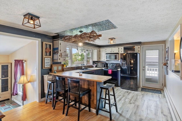 15 Lindale Ave, Biddeford, ME 04005 - kitchen with black refrigerator with ice dispenser, electric range, stainless steel microwave, a peninsula, and plenty of natural light