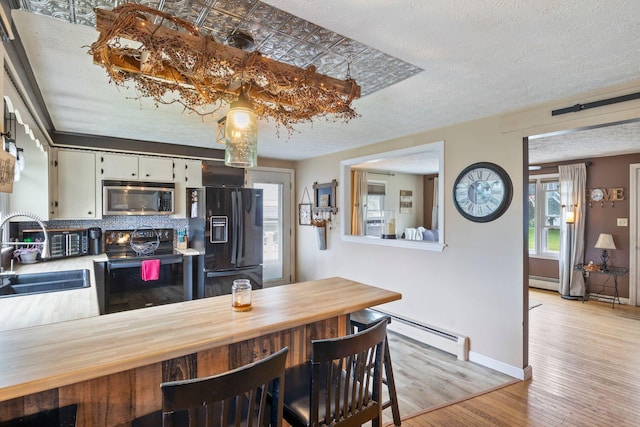 15 Lindale Ave, Biddeford, ME 04005 - dining room featuring a baseboard heating unit, light wood-style flooring, and a textured ceiling