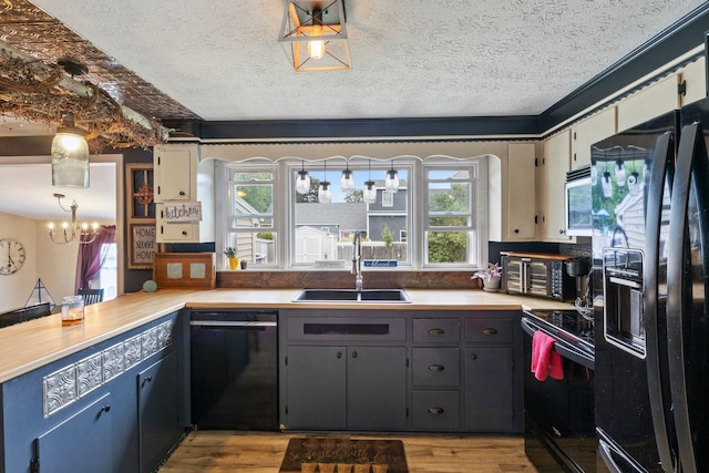 15 Lindale Ave, Biddeford, ME 04005 - kitchen featuring black appliances, healthy amount of natural light, a textured ceiling, a chandelier, and light wood-style flooring