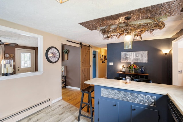 15 Lindale Ave, Biddeford, ME 04005 - kitchen with a baseboard heating unit, a barn door, light wood finished floors, blue cabinets, and light countertops