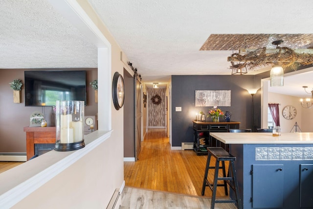 15 Lindale Ave, Biddeford, ME 04005 - kitchen featuring light wood-style flooring, a textured ceiling, a baseboard heating unit, blue cabinetry, and a baseboard radiator