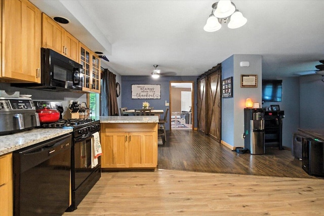 189 Old Chadbourne Rd, Lewiston, ME 04240 - kitchen featuring black appliances, a peninsula, light wood-style floors, glass insert cabinets, and light stone counters