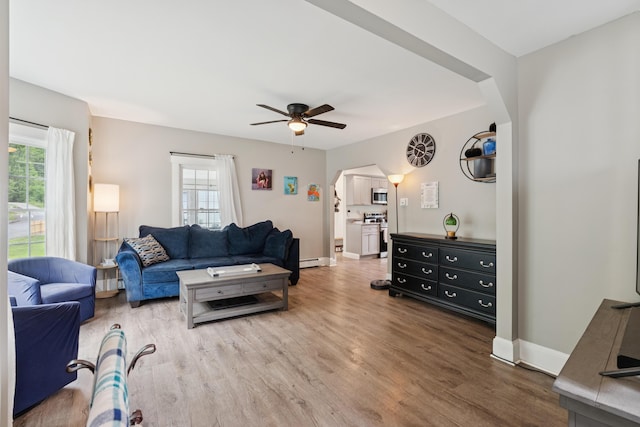 25 Searles St, Livermore Falls, ME 04254 - living area with arched walkways, plenty of natural light, wood finished floors, and a ceiling fan