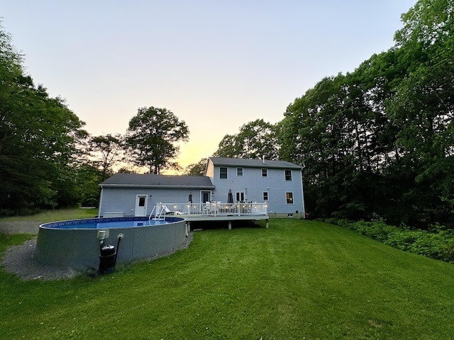 66 Stoney Acres Rd, Pittston, ME 04345 - back of property at dusk with a wooden deck, a yard, and an outdoor pool