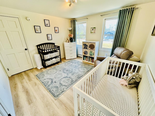 66 Stoney Acres Rd, Pittston, ME 04345 - bedroom featuring wood finished floors, a crib, and a baseboard radiator