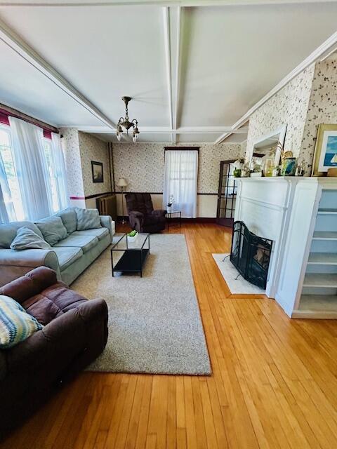 28 Holly St, Auburn, ME 04210 - living room with wallpapered walls, wood finished floors, a fireplace with flush hearth, a chandelier, and a wainscoted wall