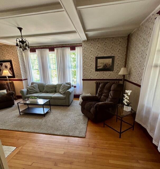 28 Holly St, Auburn, ME 04210 - living room featuring wallpapered walls, wainscoting, a chandelier, hardwood / wood-style floors, and healthy amount of natural light