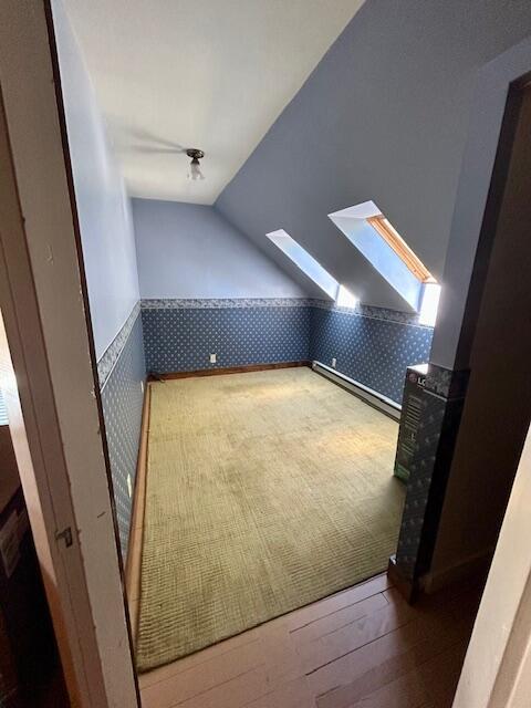28 Holly St, Auburn, ME 04210 - additional living space with wallpapered walls, wainscoting, a skylight, vaulted ceiling, and wood finished floors