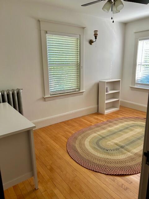 28 Holly St, Auburn, ME 04210 - unfurnished room with radiator heating unit, a ceiling fan, and wood finished floors