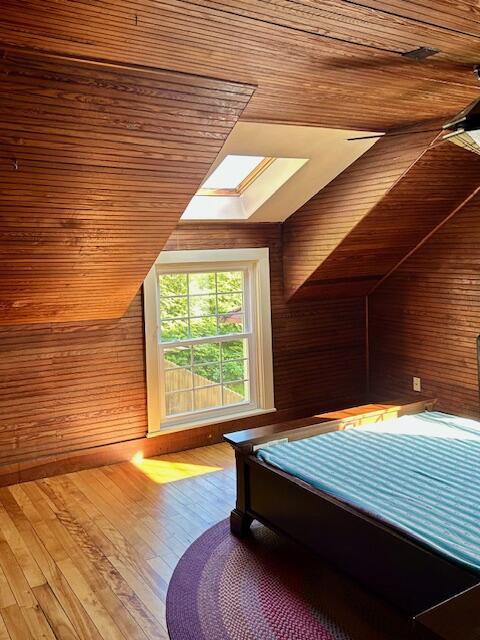 28 Holly St, Auburn, ME 04210 - bedroom with a skylight, vaulted ceiling, wooden walls, wooden ceiling, and hardwood / wood-style floors