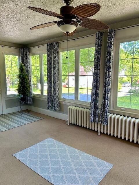 28 Holly St, Auburn, ME 04210 - sunroom / solarium with carpet flooring, a textured ceiling, plenty of natural light, and radiator heating unit
