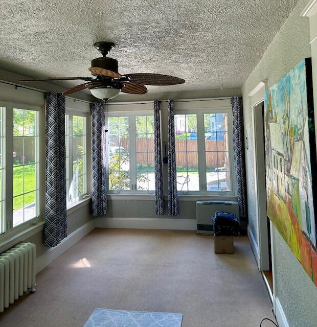 28 Holly St, Auburn, ME 04210 - unfurnished sunroom featuring radiator heating unit, a textured ceiling, and carpet