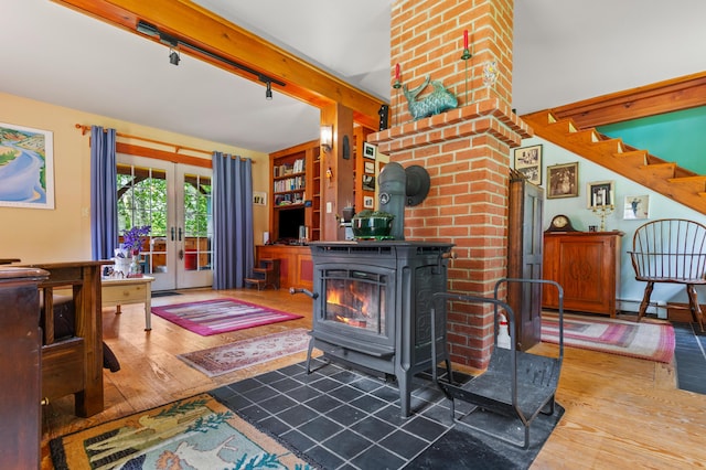 574 Mingo Loop Rd, Rangeley, ME 04970 - living room with a wood stove, french doors, rail lighting, hardwood / wood-style flooring, and a baseboard heating unit