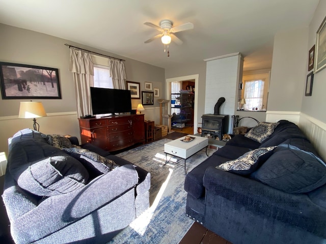86 Summer St, Saco, ME 04072 - living room featuring a wood stove, ceiling fan, plenty of natural light, wood finished floors, and a wainscoted wall