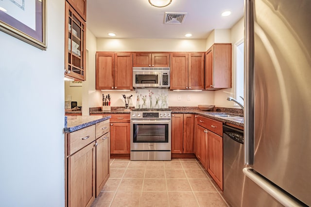 148 Breakwater Dr Unit 17, South Portland, ME 04106 - kitchen with stainless steel appliances, light tile patterned floors, dark stone countertops, brown cabinetry, and recessed lighting